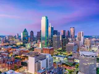Lit up Dallas skyline at dusk with buildings and skyscrapers in focus
