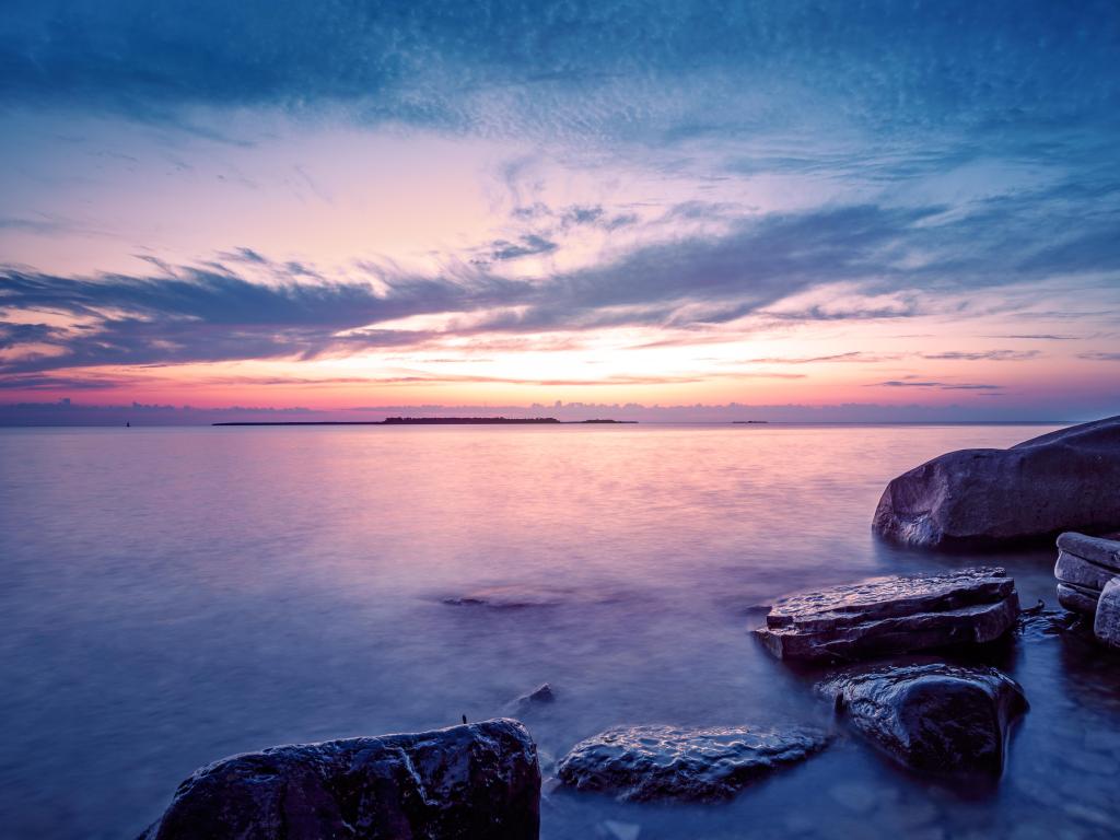 Lake Michigan, Door County, Wisconsin, USA with a dramatic coastal sunset taken at blue hour with rocks in the lake in the foreground. 