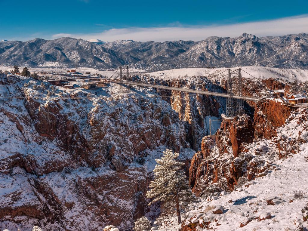 View of the Royal Gorge Bridge in winter, with snow dusting the red-toned mountains 