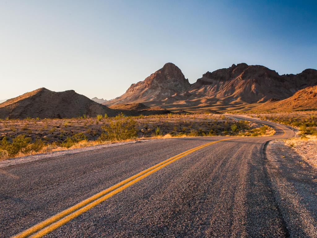 Route 66 winds through a barren area in the mountains on a hot day