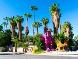 Bright pink and yellow Robolights artwork sculpture installation, surrounded by palm trees, Palm Springs, California