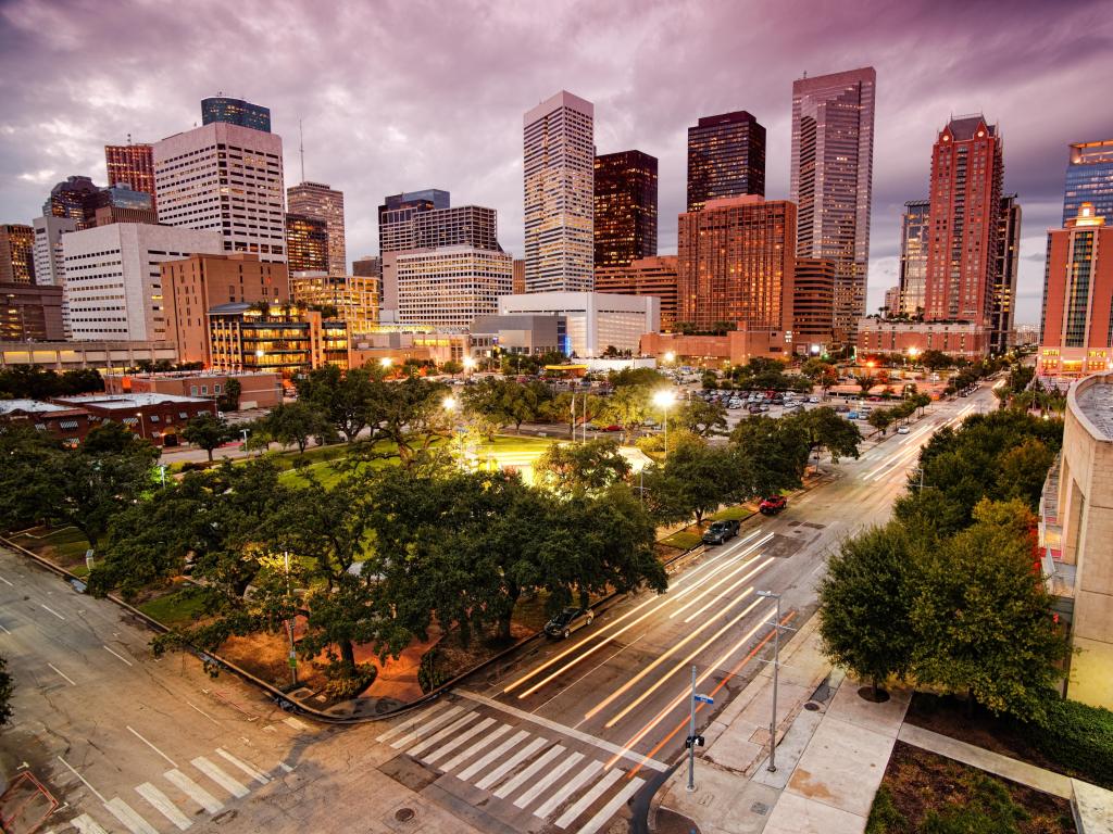 Houston, Texas, USA with downtown Houston skyline at dusk, trees in the foreground.