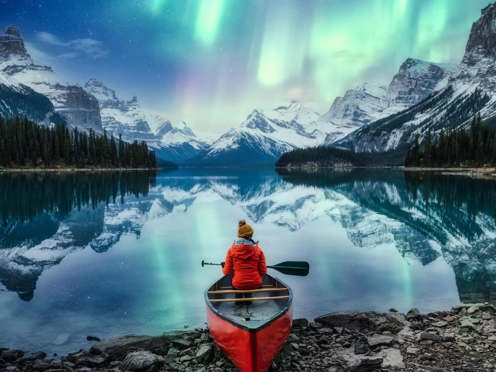 Beautiful aurora borealis over Spirit Island with female traveler on canoe at Jasper National Park