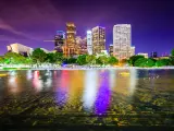 Los Angeles, California, USA downtown city skyline taken at night with the buildings reflecting in the water in the foreground.