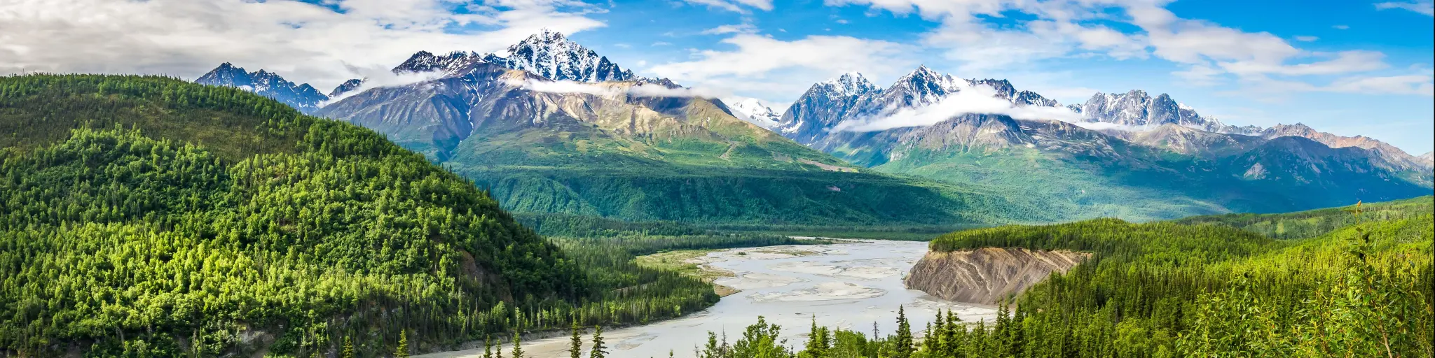 Chugach Alaska Range with a beautiful river cutting across a green forest with mountains as the backdrop