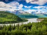 Chugach Alaska Range with a beautiful river cutting across a green forest with mountains as the backdrop