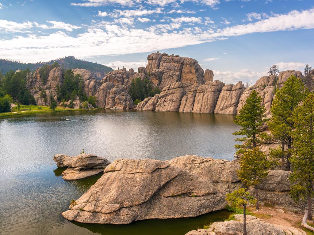 Custer State Park, Custer, USA with a view of Sylvan Lake, boulders in the distance and rock formations in the distance, on a sunny day.