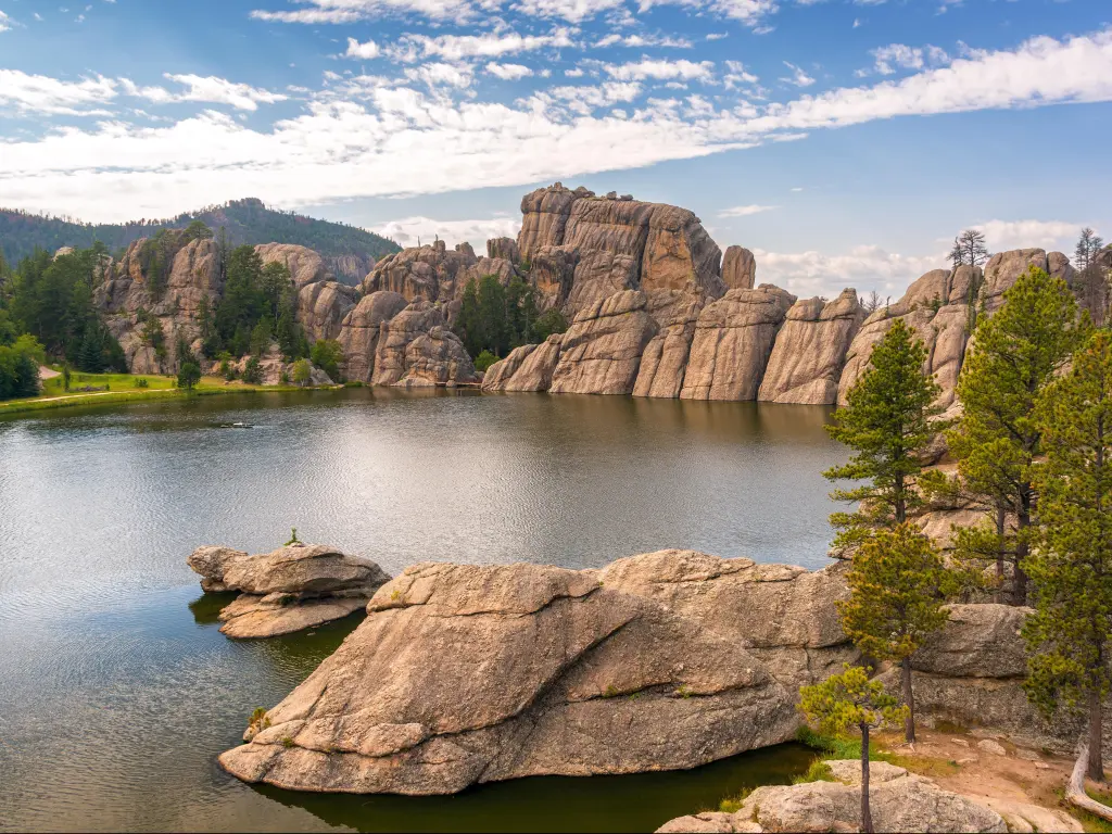 Custer State Park, Custer, USA with a view of Sylvan Lake, boulders in the distance and rock formations in the distance, on a sunny day.