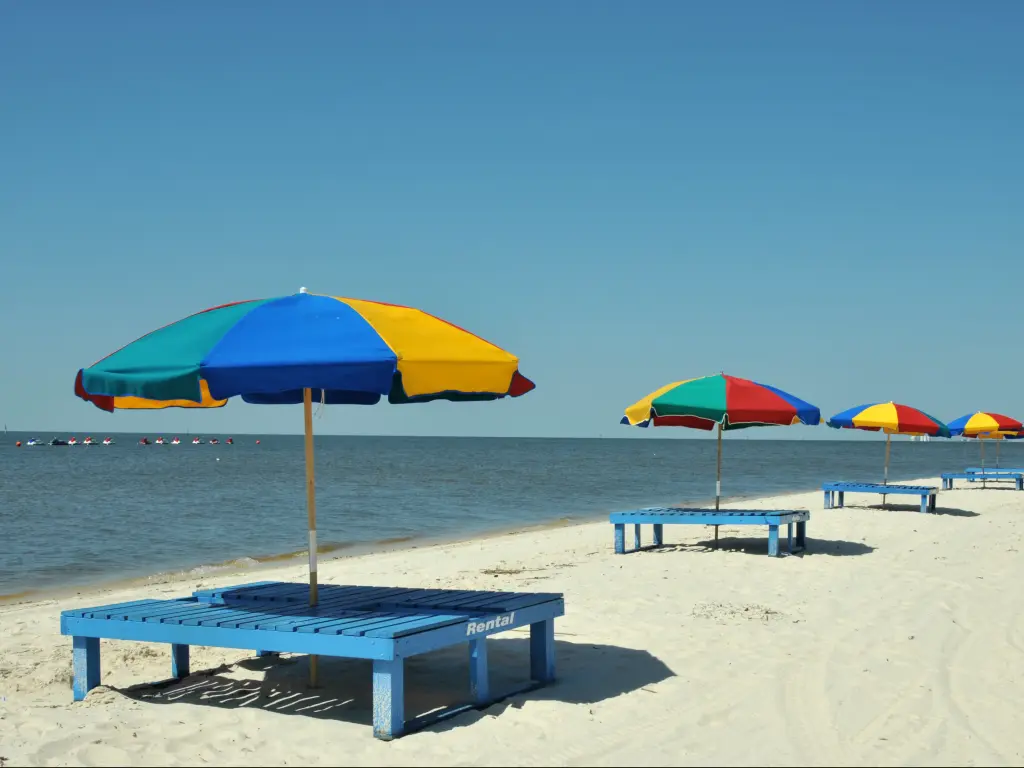 Colorful umbrellas and lounge chairs by the sea in Biloxi Beach near Ocean Springs, Mississippi.