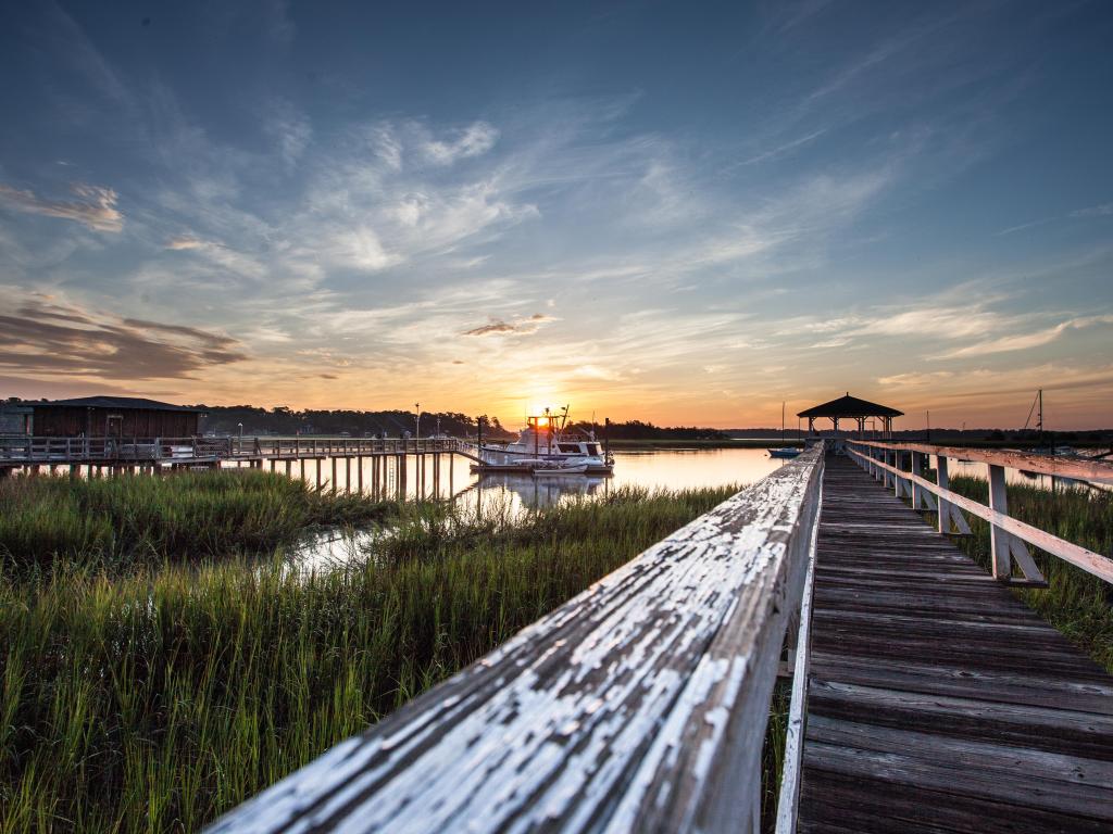 Old wooden dock leading to a beautiful sunrise over the marsh in Savannah, Georgia, USA