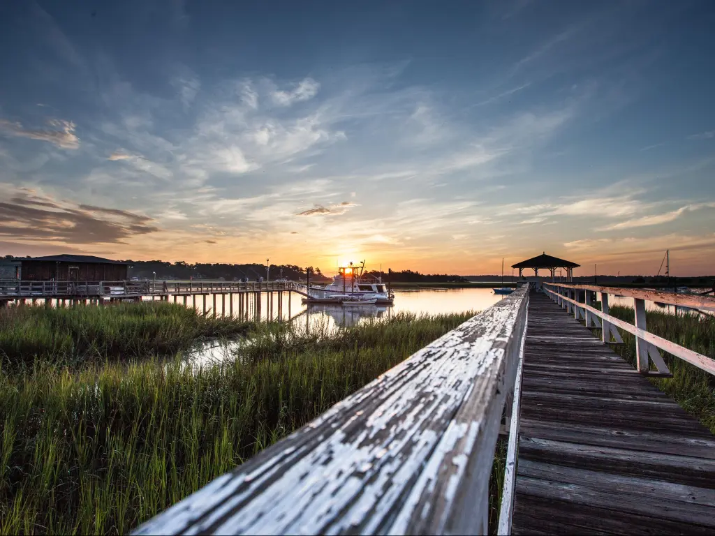 Old wooden dock leading to a beautiful sunrise over the marsh in Savannah, Georgia, USA
