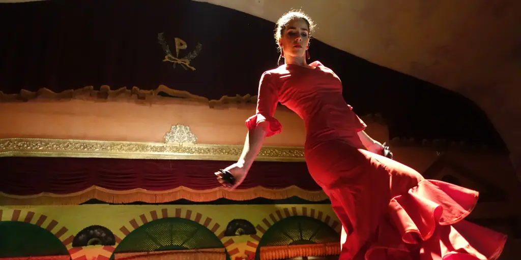 A flamenco dancer in a red dress dances on a stage in Sevilla