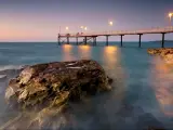 Darwin, NT, Australia with a view of the Nightcliff Jetty taken at early evening with rocks in the water and street lamps on.