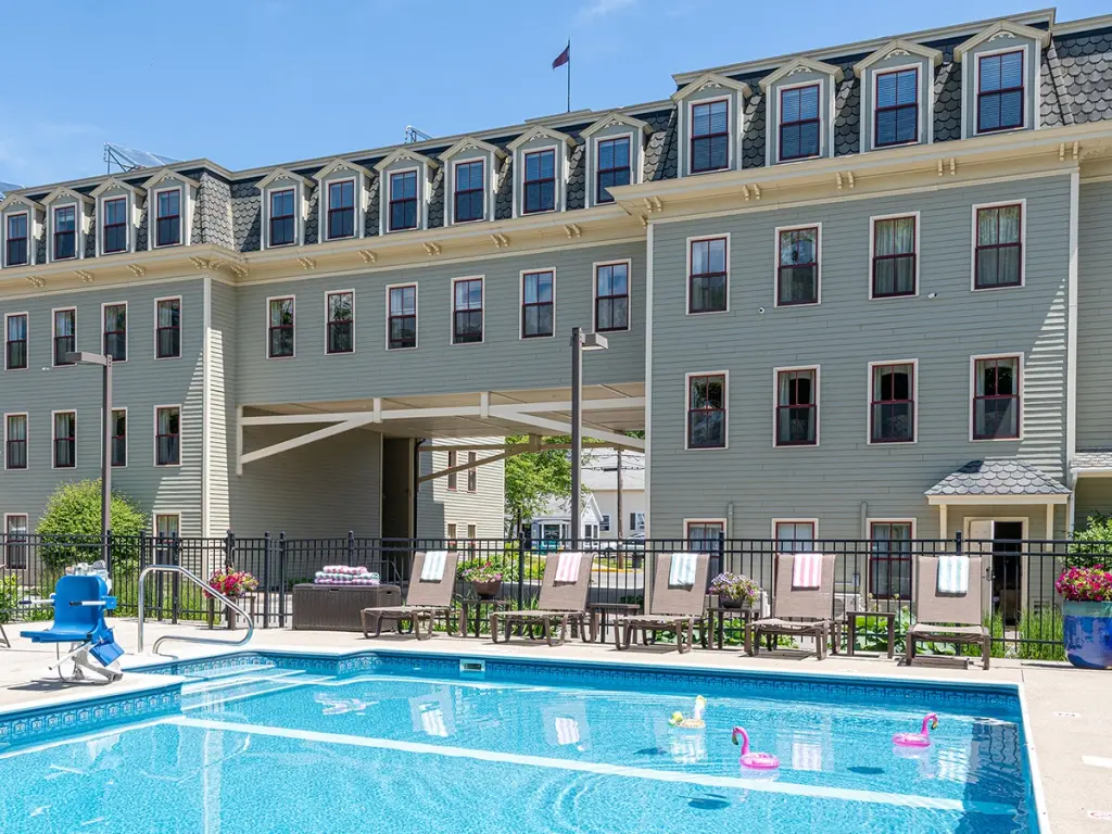 Outdoor pool of the hotel with sitting area, with the hotel's main building in the background