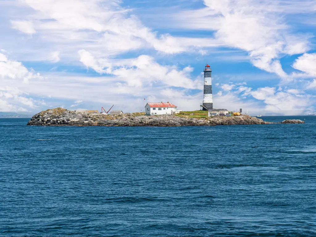 Lighthouse on a small rocky island in the sea on a partially cloudy day