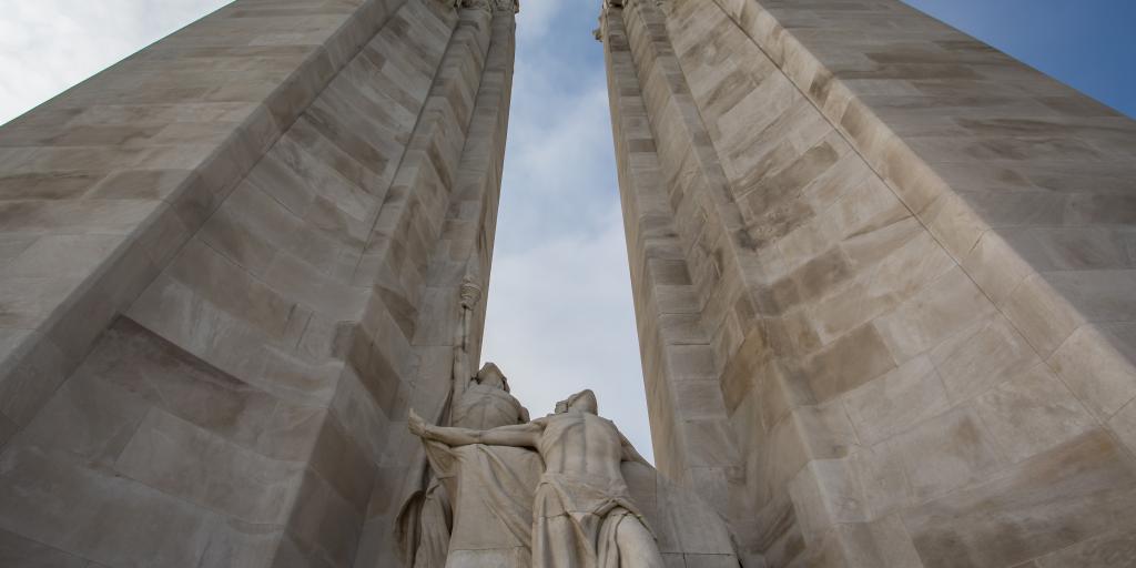 The two towers of the Canadian National Vimy Memorial, France, seen from the bottom, with a sculpture of two people looking up between them