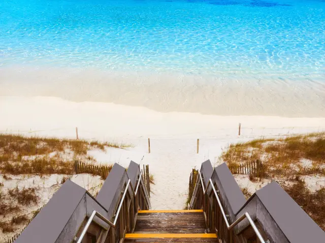 Stairs leading down to the beach with crystal blue ocean waters in the distance