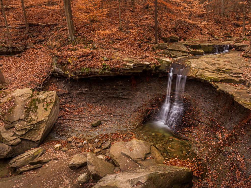 An aerial view of Blue Hens Falls in Cuyahoga Valley National Park during fall the land and big rocks is covered with leaves.  