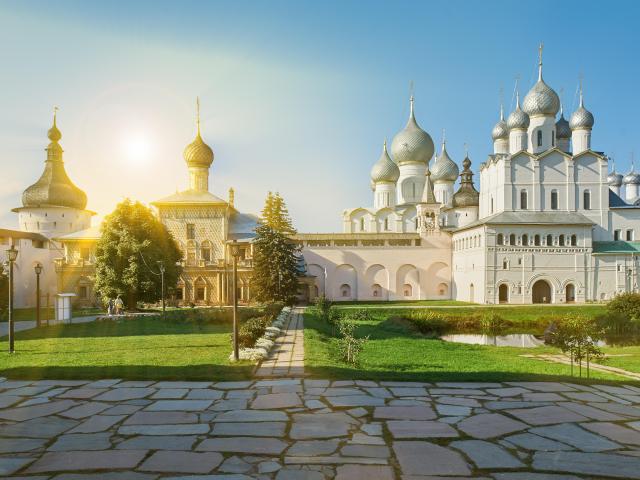 Sunlight streaming onto the white Assumption Cathedral and church of the Resurrection in Rostov Kremlin.