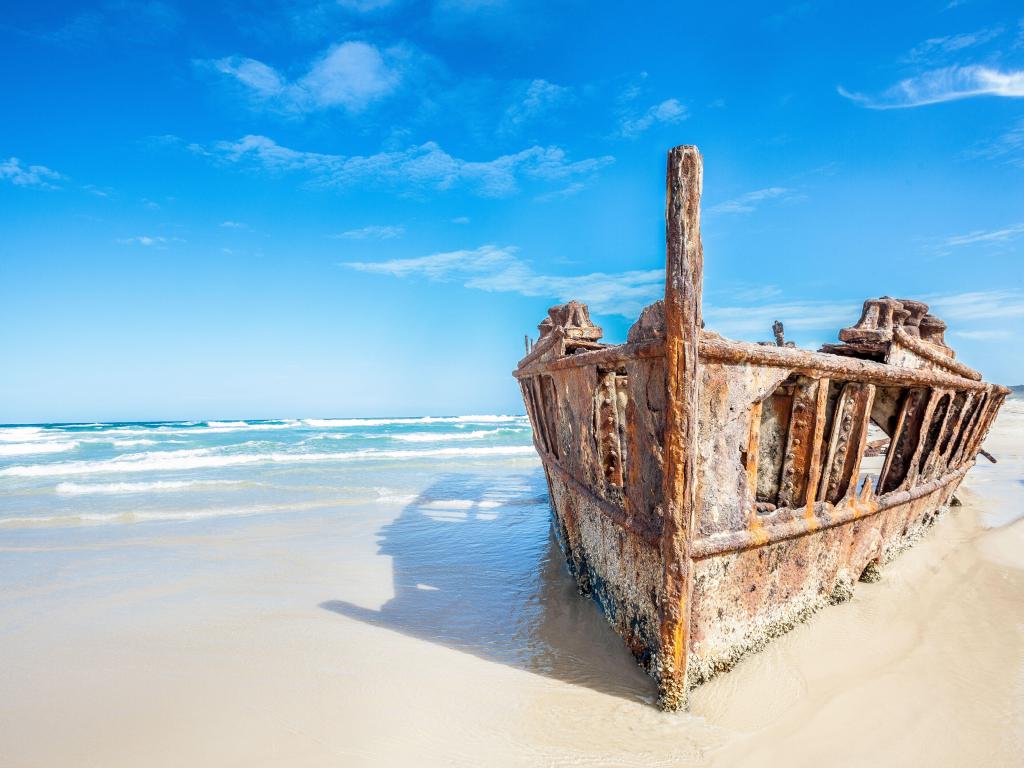 Fraser Island, Queensland, Australia  with a view of the iconic ship wreck surrounded by white sand on a sunny day.