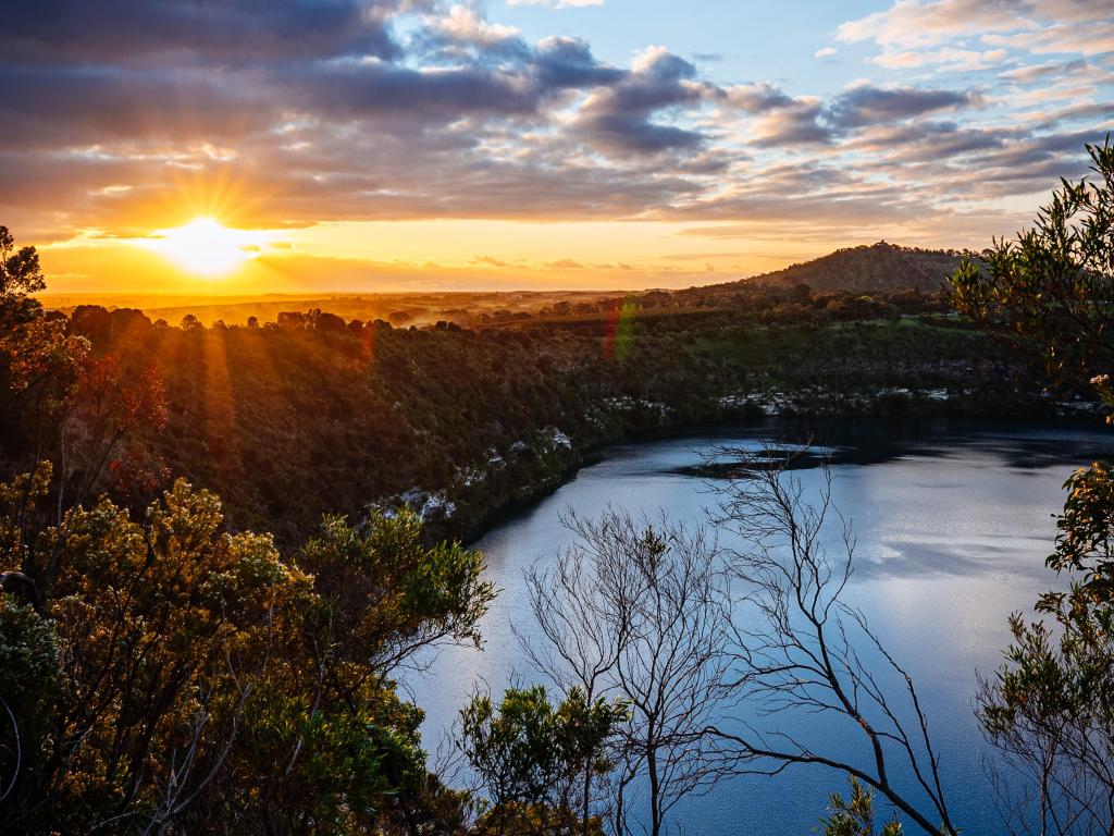 Setting sun behind lake with trees all around steep sided shores