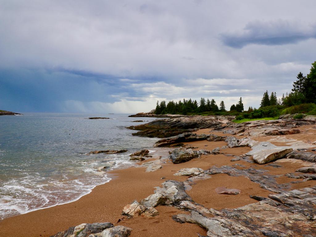 Reid State Park, Maine, USA with a shot of the scenic shoreline view with trees in the background. 