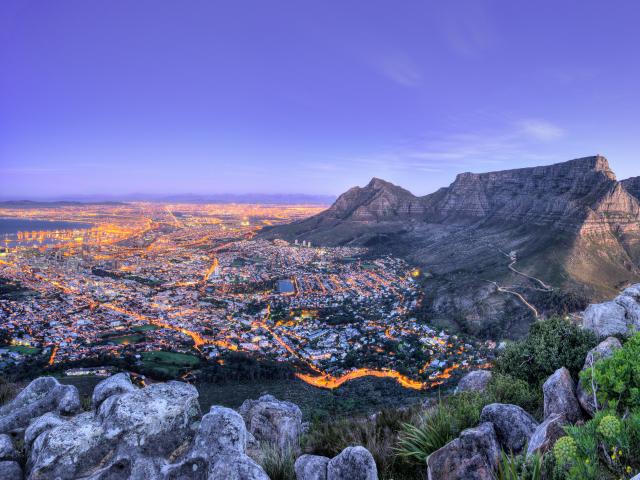 Cape Town, South Africa with Table Mountain in the distance and the city below at night.
