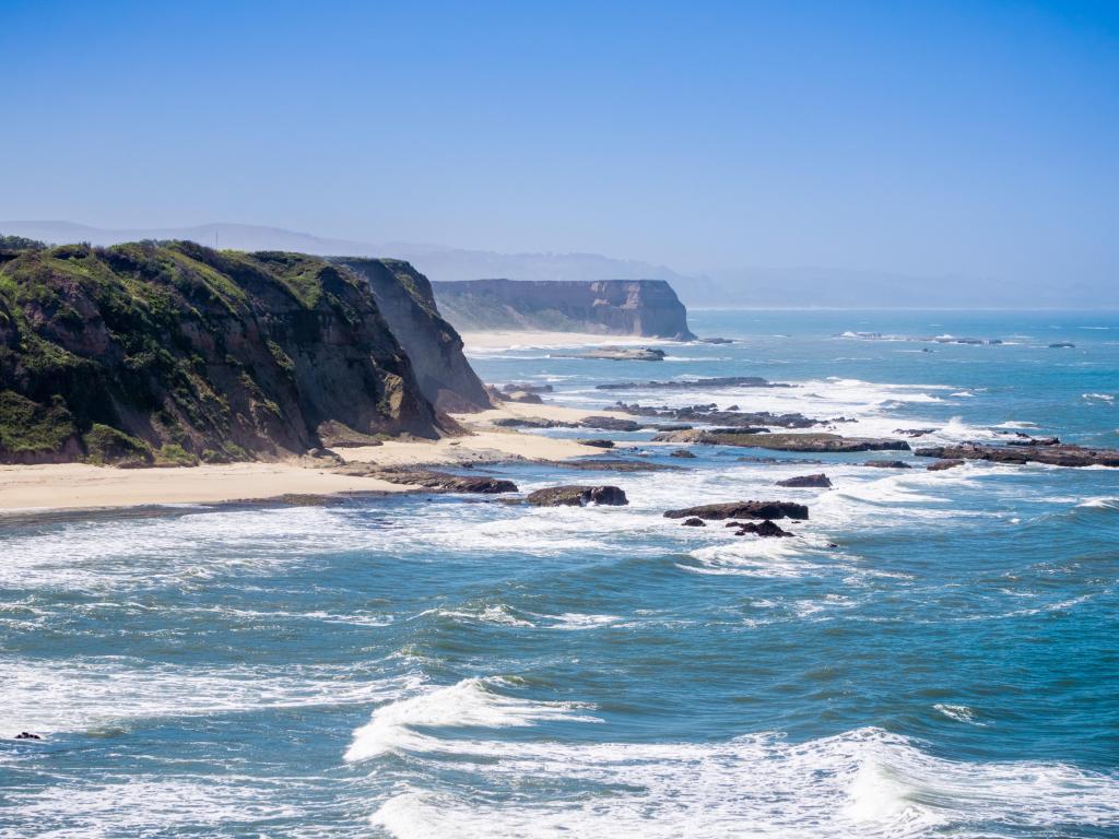 Cliffs on the Pacific Ocean coastline near Half Moon Bay, California, with a blue sky