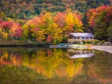Boathouse surrounded by autumn trees, reflecting in Echo Lake, in Franconia Notch State Park, New Hampshire
