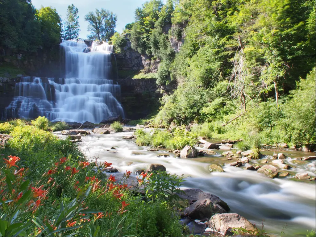 Syracuse, New York, USA with a waterfall taken on a sunny day surrounded by greenery. 