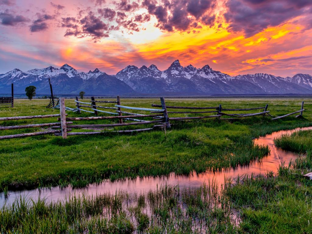 Golden Fiery Sunset at Grand Teton - A colorful spring sunset at Teton Range, seen from an abandoned old ranch in Mormon Row historic district, in Grand Teton National Park, Wyoming, USA.