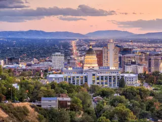 Salt Lake City skyline at night with mountains in the background and a mixture of buildings in the foreground.