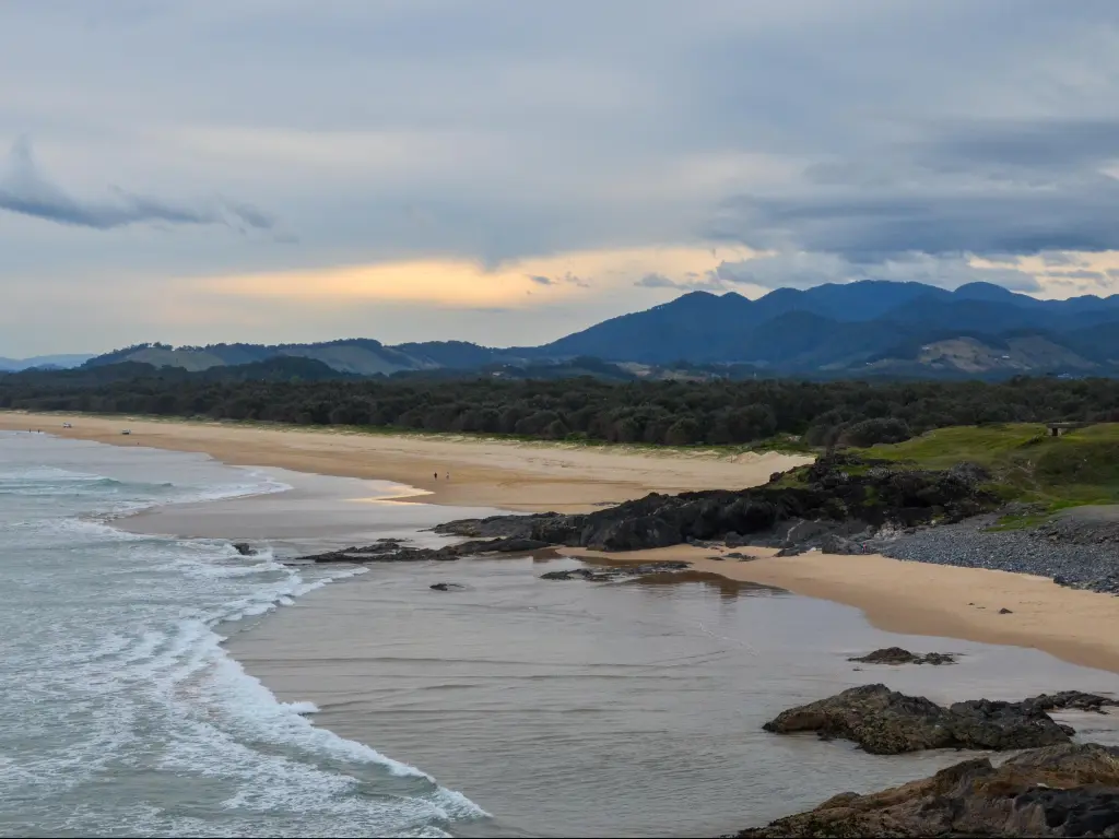 Coffs Harbour, Australia with a view of the beach and mountains in the distance at sunset.