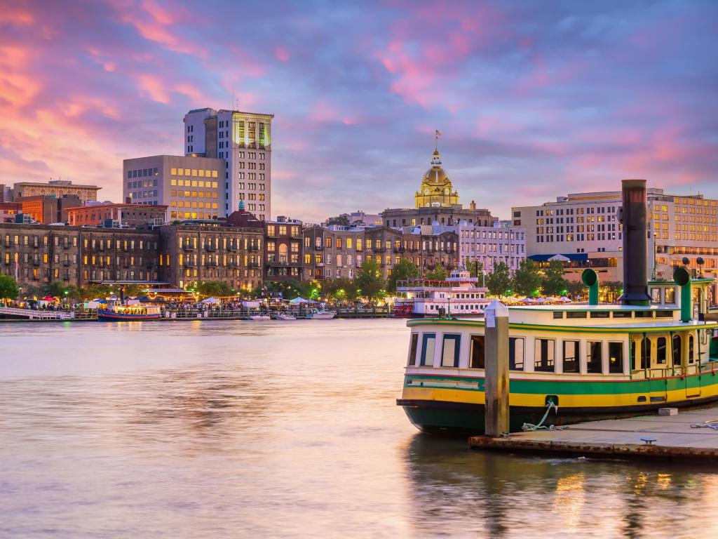 Savannah, Georgia USA taken at sunset at the historic district with a long boat in the foreground and the city in the background. 