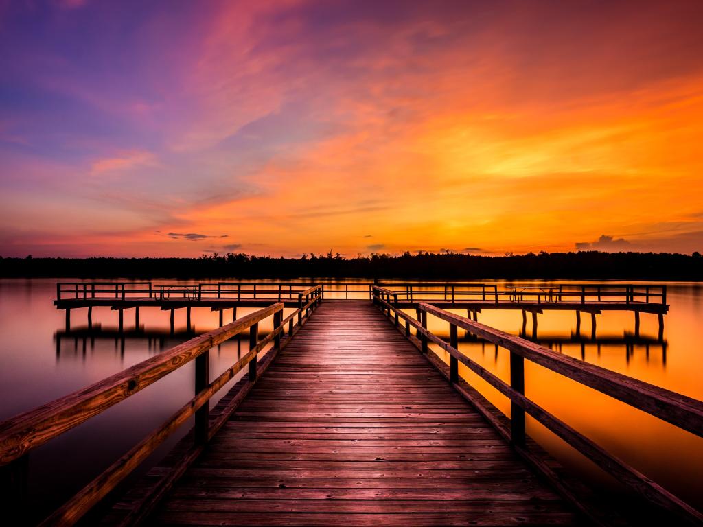 Elvis Presley Lake, Tupelo, Mississippi, USA taken at evening with a stunning sky of red and purple and a wooden pier leading to the lake.