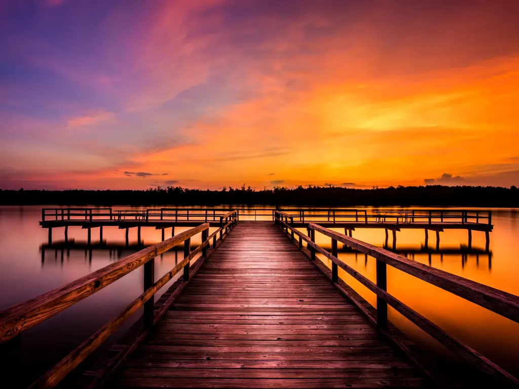 Elvis Presley Lake, Tupelo, Mississippi, USA taken at evening with a stunning sky of red and purple and a wooden pier leading to the lake.