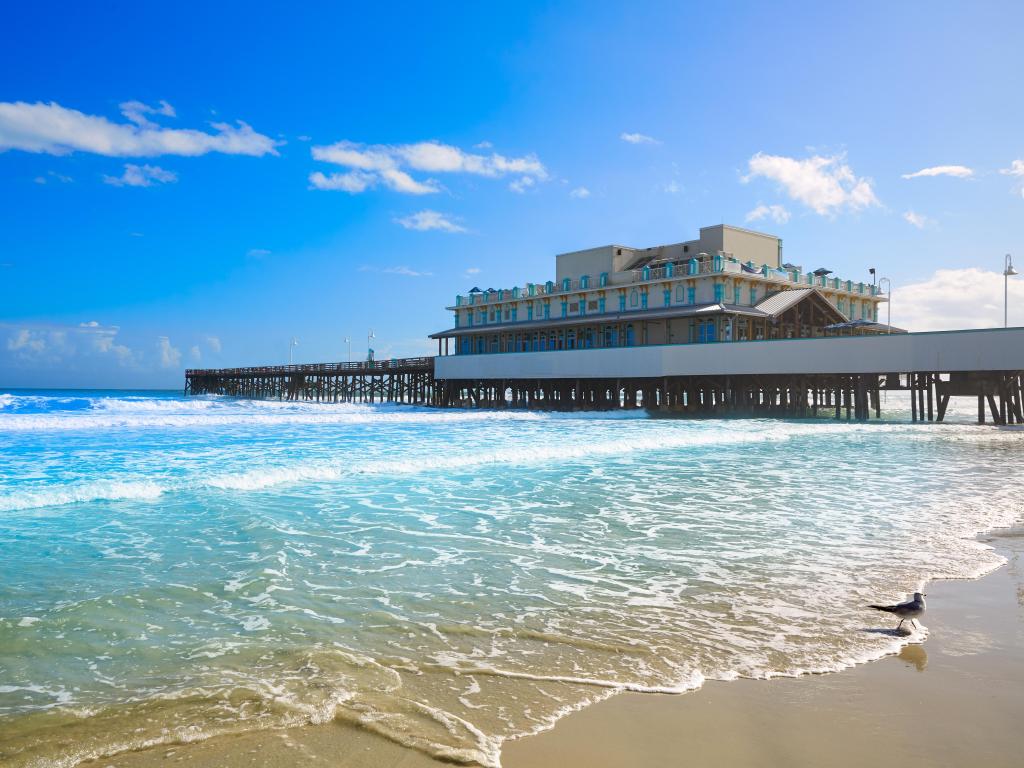 Daytona Beach in Florida with pier and coastline USA on a nice, sunny day with beautiful waves crashing on the beach.