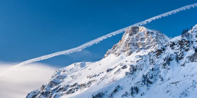 The Rocher de Charvet peak in the resort of Val d'Isere with an aeroplane trail behind it