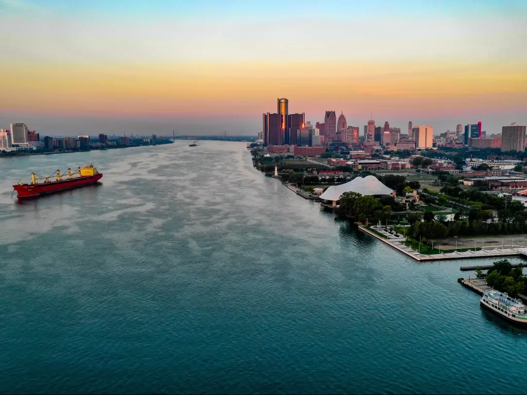Aerial shot of Detroit Riverfront at dusk, with a large ship passing by