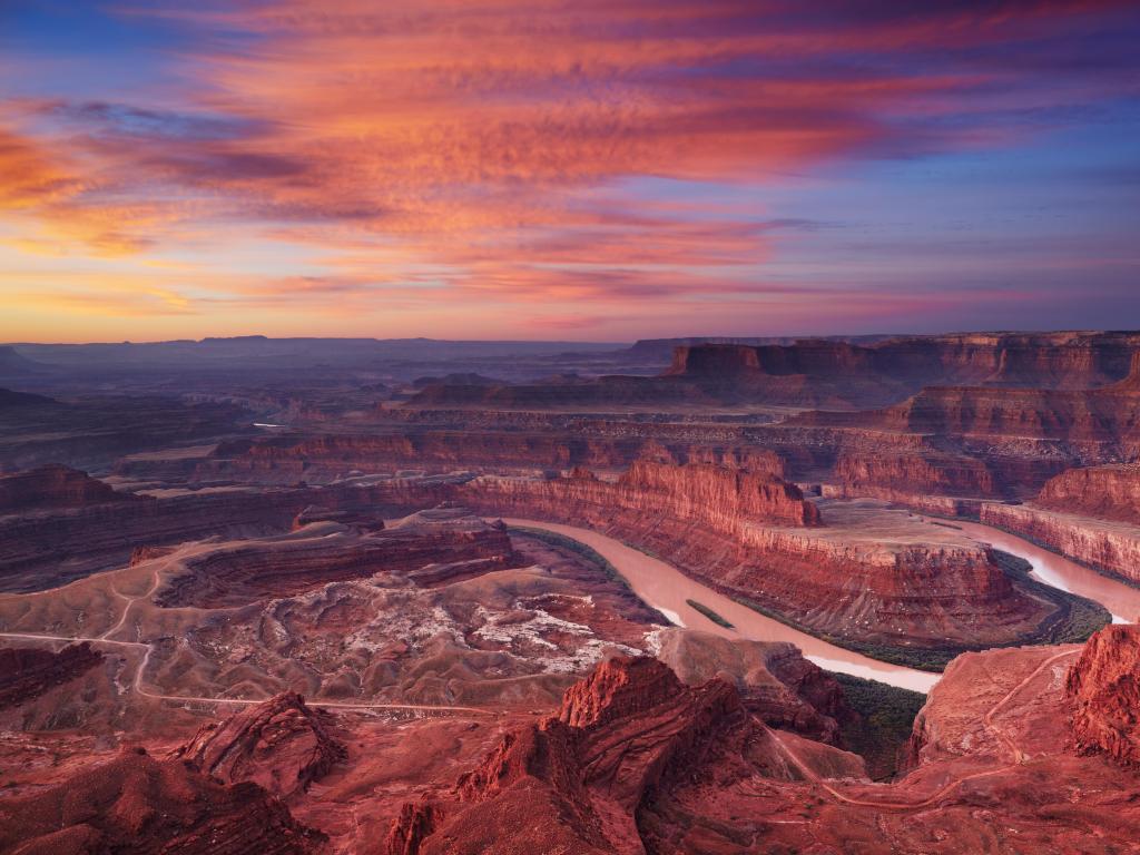 Dead Horse Point, Colorado river, Utah, USA taken during a colorful sunrise with a red sky looking down to the river and canyons below.