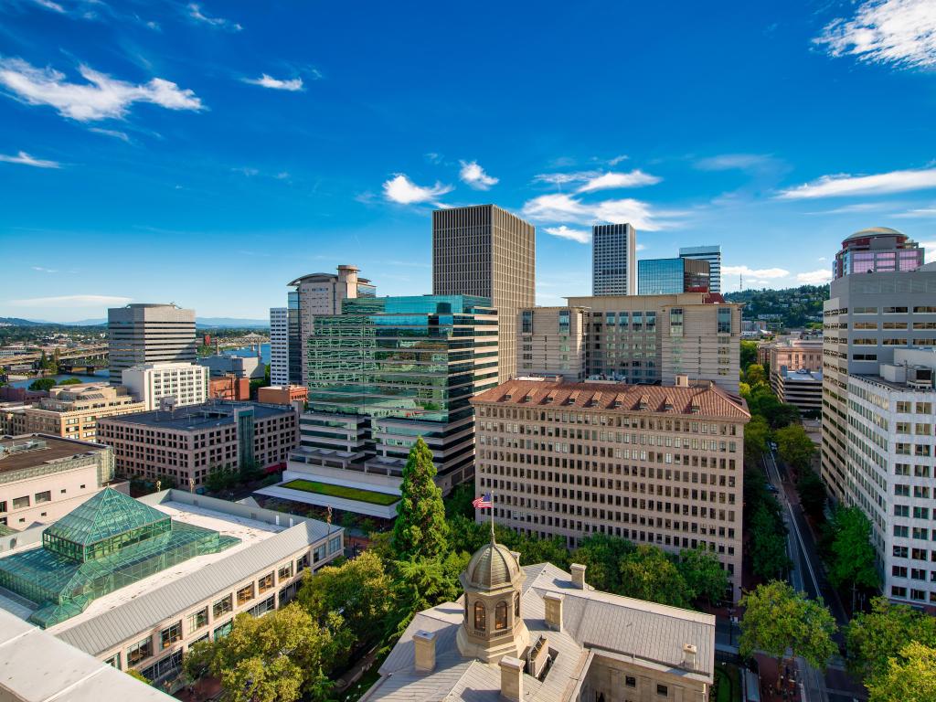 Portland, Oregon, USA with buildings and skyscrapers taken as an aerial view against a blue sky.