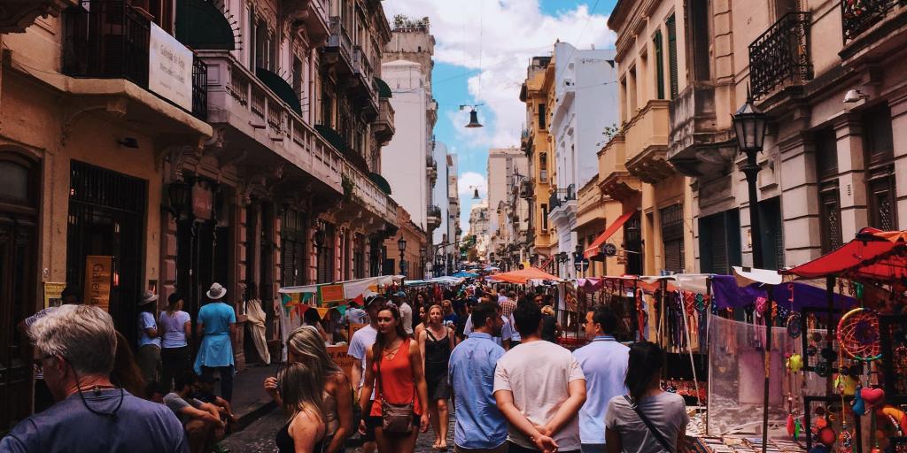 People walking through a street market in San Telmo, Buenos Aires, Argentina, with tall colonial buildings each side