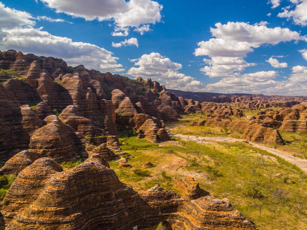 Purnululu National Park, Bungle Bungles, Western Australia with a path between unique mounds leading into the distance on a sunny day.