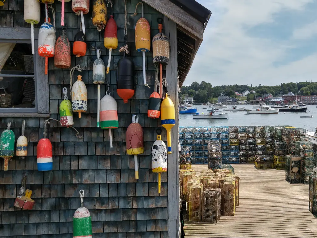 New England Lobster Fishing Dock Marker buoys for lobster traps decorate the side of a fishing shack on a wharf in Maine.