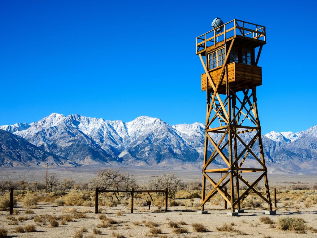 Wooden watchtower in the desert, mountains in the background on a sunny day