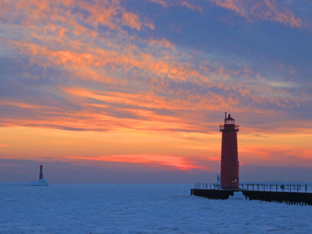 Lighthouse at the end of Muskegon Pier, overlooking Lake Michigan in winter during sunset.