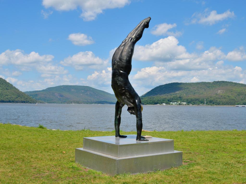 The Golden Mean Sculpture created by Carole Feuerman, seen with Peekskill Bay in the background on a sunny day