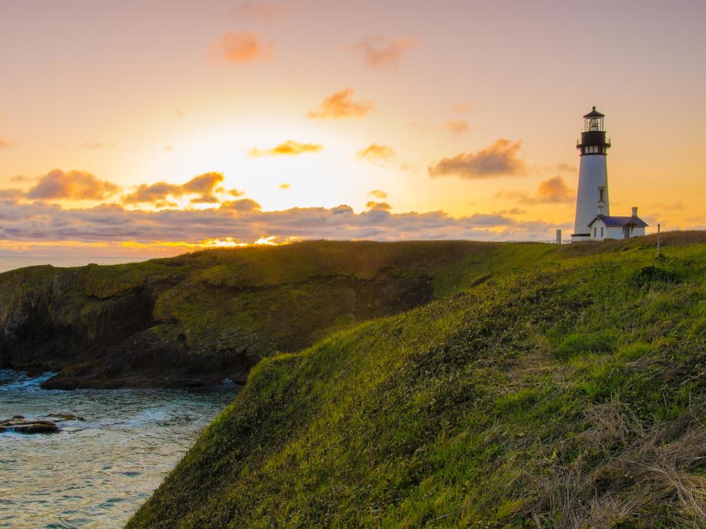 Beautiful white lighthouse on a cliff during sunset