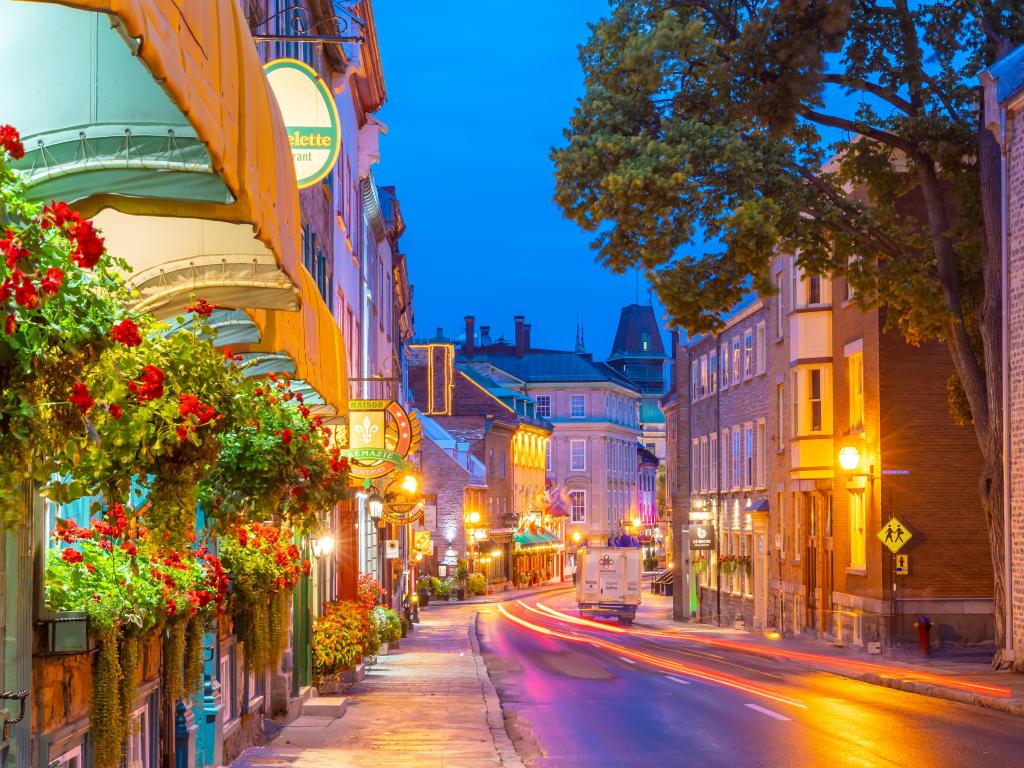 Quebec City, Quebec, Canada taken at the old town area at twilight with street lights and flowers on the shop fronts down the street.