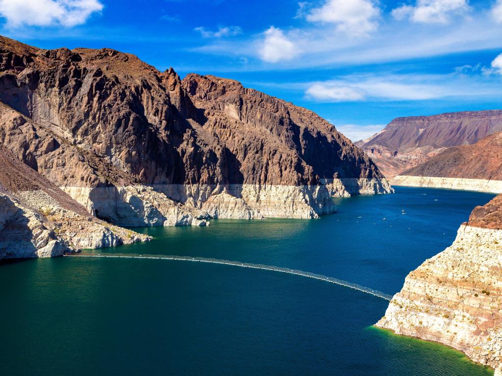 Hoover Dam, Nevada and Arizona border, USA with a view of the Colorado River and cliffs either side against a blue sky.